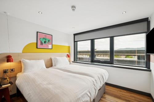 a bedroom with a large bed and a large window at Garner Hotel Edinburgh - Haymarket by IHG in Edinburgh