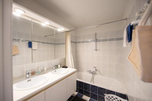 Un baño con lavabo, espejo y bañera. en Gauguin F 0602, en Nieuwpoort