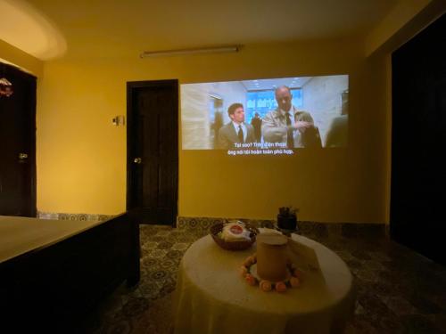 a room with a table and a tv on the wall at Daisy Homestay Hoian in Hoi An