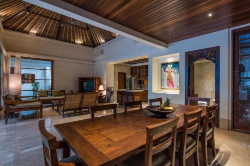 een eetkamer met een houten tafel en stoelen bij Villa Senada by Nakula in Jimbaran