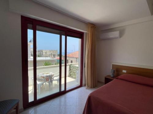 a bedroom with a bed and a glass door to a balcony at Hotel Lungomare Brancaleone in Brancaleone Marina