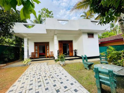 a white house with two benches in front of it at Bentota Upali Villa in Bentota