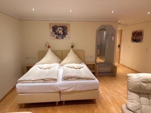 a bedroom with a bed and a chair at Engelhard Das Landhotel Garni in Kirchheim am Ries