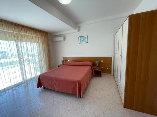 a bedroom with a bed and a large window at Hotel Lungomare Brancaleone in Brancaleone Marina