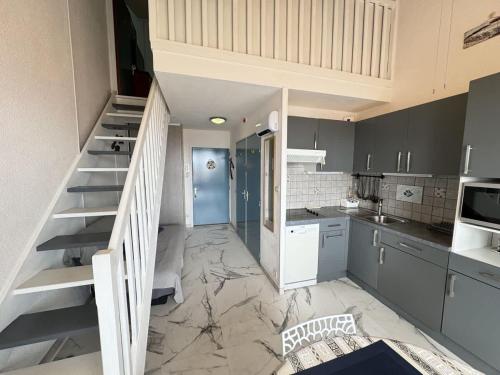 une cuisine avec un escalier au milieu d'une pièce dans l'établissement Valras-Loc Vue sur la Ville et Apercu de la Mer, à Valras-Plage