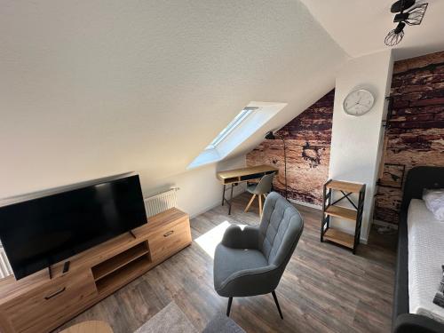a living room with a flat screen tv and a chair at Ferienwohnung Zeitz - Weiße Elster Apartment in Zeitz