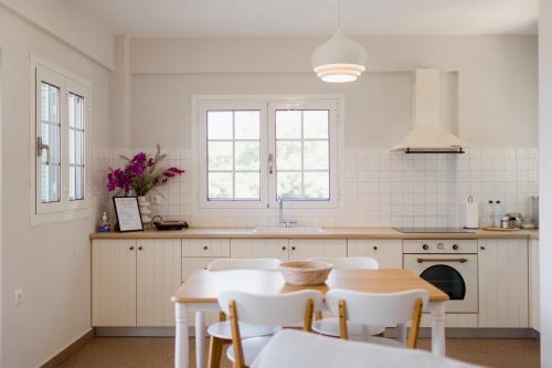 een witte keuken met een tafel en witte stoelen bij Locanda Villas in Lefkada