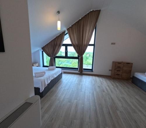 a bedroom with two beds and large windows at INDRA WELLNESS Retreats and Spa in Samurcaşi