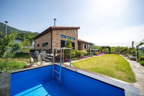 a house with a blue pool in front of a yard at Cheongdo Peach Blossom Private Pension in Sora