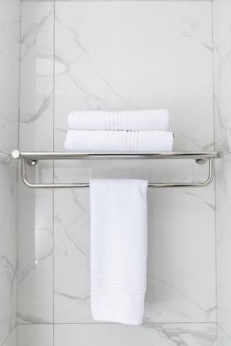 a stack of towels on a towel rack in a bathroom at Illovo Hotel in Johannesburg