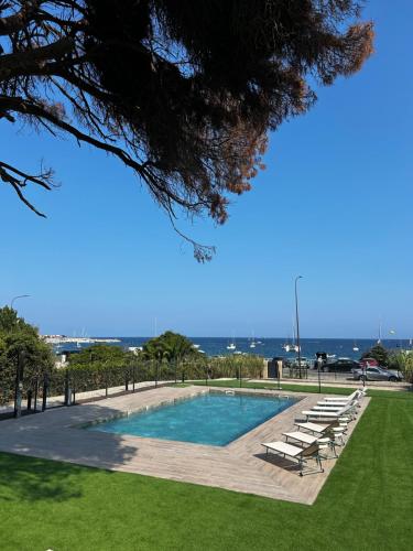 une piscine avec des chaises longues et l'océan en arrière-plan dans l'établissement Charmante maison face à la mer, à Sainte-Maxime