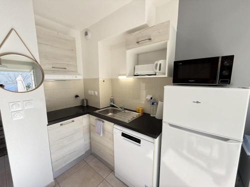 La cuisine blanche est équipée d'un réfrigérateur et d'un évier. dans l'établissement Valras-Loc La Dune - Evasion Cotiere Havre de Paix, à Sérignan