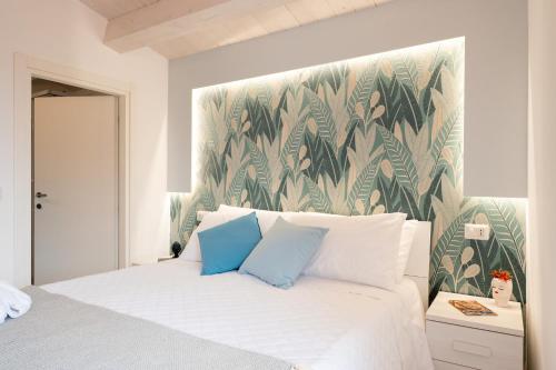 a bedroom with a white bed with a tropical wallpaper at Vico degli Orti in Mistretta