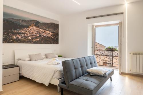 a white bedroom with a bed and a chair at Vico degli Orti in Mistretta