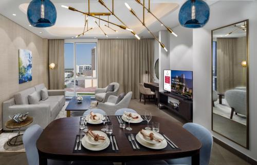 a dining room and living room with a table and chairs at Millennium Residences Saadiyat Island in Ḩayl
