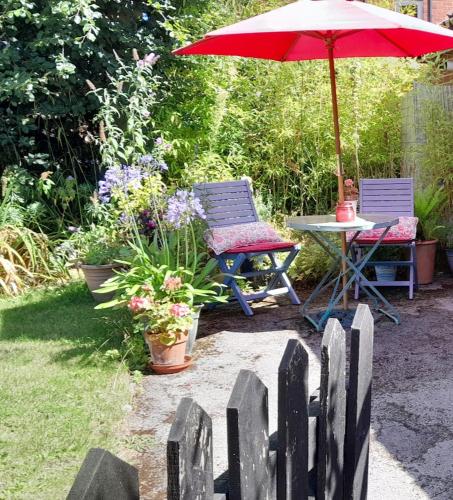 a garden with two chairs and a table with an umbrella at Rosehips at Kerensa, Naburn in York