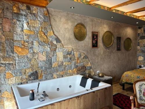 a bath tub in a room with a stone wall at Vila Eden Boutique Hotel in Korçë