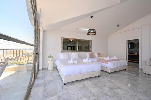a bedroom with two beds and a large window at Villa Blue Horizon in Tiberias
