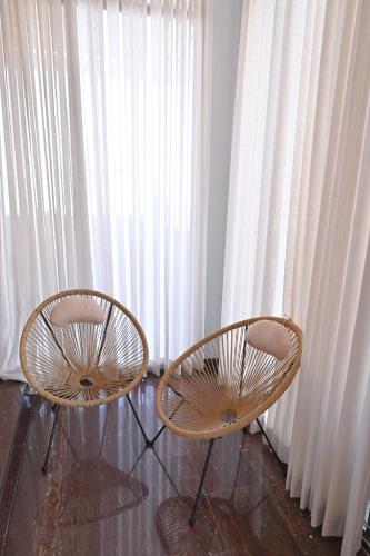 two chairs in front of a window with curtains at Villa Blue Horizon in Tiberias