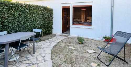 un patio avec une table et des chaises à côté d'un bâtiment dans l'établissement Studio ouest à 300m des plages, à Mimizan