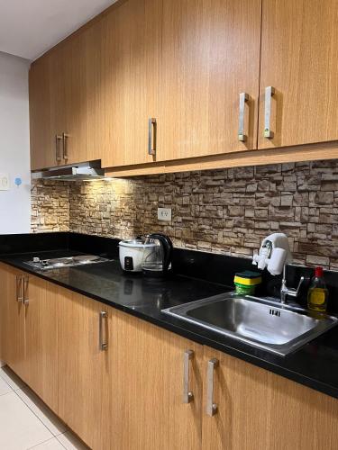 a kitchen with a stainless steel sink and wooden cabinets at Sea Residences Mall of Asia Viann in Manila