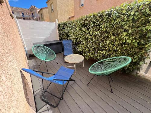 trois chaises et une table sur une terrasse dans l'établissement Valras-Loc Le Bonheur a la Plage, à Valras-Plage