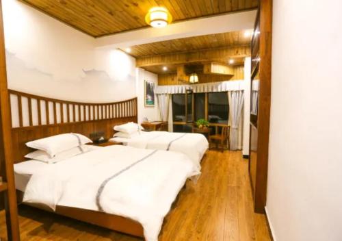two beds in a bedroom with white sheets at Huazhu Xizhou Impression Inn Furong Town Waterfall Branch in Wang-ts'un