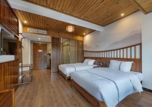 two beds in a bedroom with wooden walls and wooden floors at Huazhu Xizhou Impression Inn Furong Town Waterfall Branch in Wang-ts'un