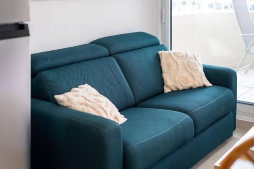 - un canapé bleu avec 2 oreillers dans l'établissement 66 Suite A108, à Valras-Plage
