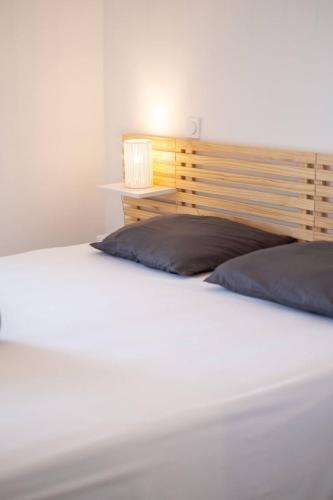 - un lit blanc avec une tête de lit en bois dans l'établissement 66 Suite A108, à Valras-Plage