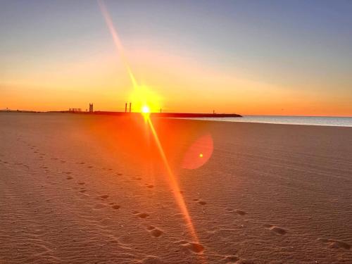 un coucher de soleil sur une plage avec des empreintes sur le sable dans l'établissement Maison Sympa, à Valras-Plage