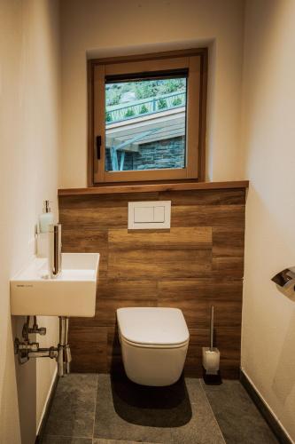 a bathroom with a toilet and a sink and a window at Rufana Alpin in Bürserberg