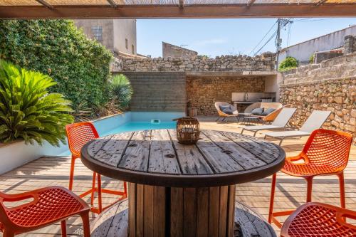 un patio extérieur avec une table et des chaises en bois dans l'établissement Maison de Village en Pierre Piscine - 8 personnes, à Lansargues