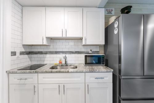 a kitchen with white cabinets and a stainless steel refrigerator at 301 Ocean Ave, Unit 109 - The Harbor Light in North Wildwood