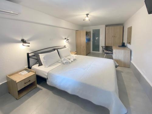 a bedroom with a large white bed and a kitchen at Ammolithos Beach in Stavros