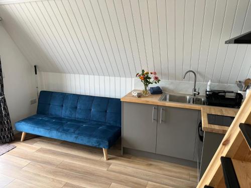 a blue couch in a kitchen with a sink at Tiny home on an organic croft, Isle of Arran in Kildonan