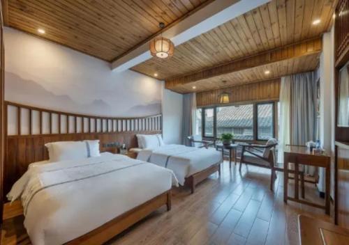 a bedroom with two beds and a table with a desk at Huazhu Xizhou Impression Inn Furong Town Waterfall Branch in Wang-ts'un