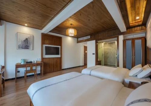 a bedroom with two beds and a flat screen tv at Huazhu Xizhou Impression Inn Furong Town Waterfall Branch in Wang-ts'un