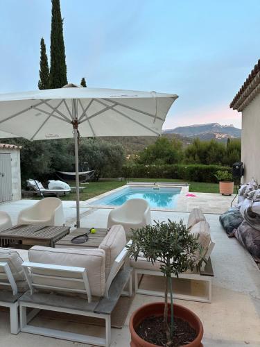 un patio avec un parasol et des chaises et une piscine dans l'établissement Maison à la campagne avec piscine, à Auriol