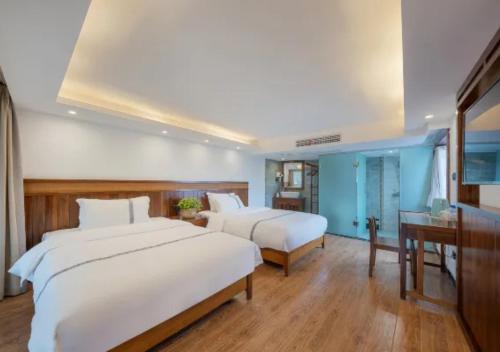 two beds in a bedroom with blue walls and wooden floors at Huazhu Xizhou Impression Inn Furong Town Waterfall Branch in Wang-ts'un