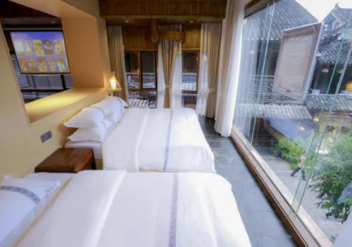 a room with three beds and a large window at Huazhu Xizhou Impression Inn Furong Town Waterfall Branch in Wang-ts'un