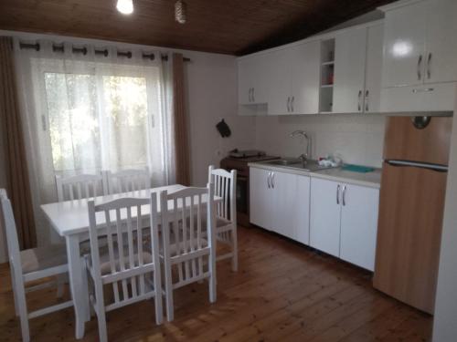 een keuken met witte kasten en een tafel en stoelen bij Oasis Villa in Shtoji i Ri