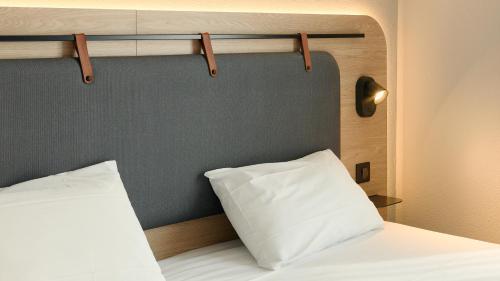 a bed with a white pillow and a gray wall at Campanile PRIME - Paris 15 Tour Eiffel in Paris
