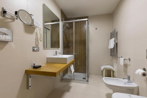 a white bathroom with a sink and a shower at Hotel Royal Caserta in Caserta