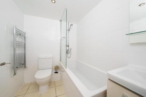a white bathroom with a toilet and a shower at Modern 3BR - Flat Sleeps 8 - Walk to Liverpool St in London