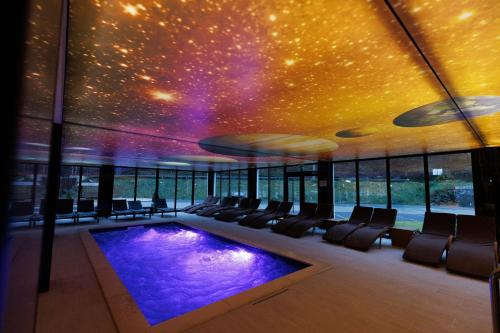 a room with a swimming pool and a ceiling with stars at Nedei Hotel&Spa Transalpina in Martinie