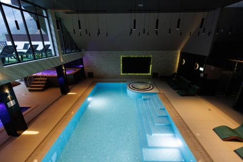 a swimming pool in a building with a large window at Nedei Hotel&Spa Transalpina in Martinie