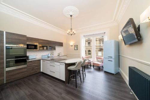 a kitchen with white cabinets and a blue refrigerator at Cordis Apartment in Dundee