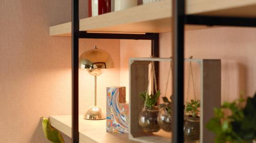 a shelf with a lamp and potted plants on it at Campanile PRIME - Paris 15 Tour Eiffel in Paris