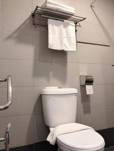 a bathroom with a white toilet and towels at Tumike Hotel Bentong in Bentong